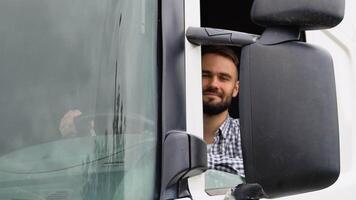A driver sitting inside the semi-truck while looking at camera through the open window video