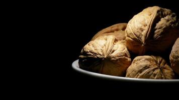 Walnuts in a bowl at right of screen in rotation on black background video