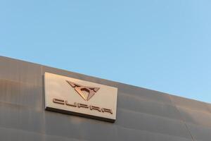Torrevieja, Spain - 09-07-2024, Cupra logo prominently displayed against a modern building facade under a clear blue sky, perfect for showcasing automotive branding and dealership design elements. photo