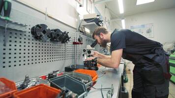 Diagnostics of diesel injectors under a microscope. The master examines the nozzle under a microscope to detect defects. video