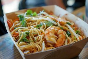 Delicious asian noodles with shrimps and vegetables in take away box photo