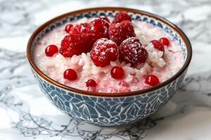 Bowl of rice pudding with fresh raspberries and redcurrants being sprinkled with powdered sugar photo