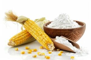 Corn starch powder in wooden bowl with scoop and corn cobs on white photo