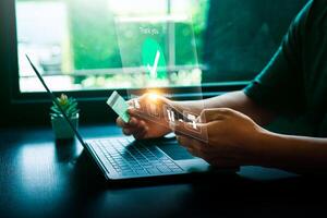 Person Making Online Payment with Credit Card on Laptop, Holographic Interface Showing Payment Successful and Shopping Icons, Representing E-commerce and Digital Transactions photo