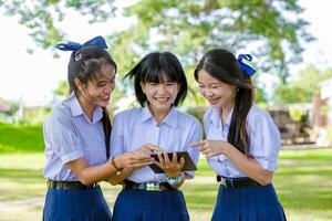 Group of Asian school girls teen friend in school uniform together look tablet happy smiling photo