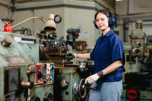 Portrait happy engineer worker with safety eyes protection glasses professional working with metal lathe milling machine heavy industry factory. photo