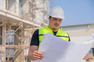 Construction Worker Reviewing Blueprints at Building Site photo