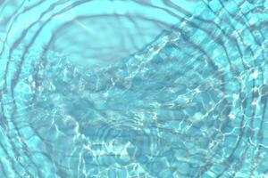 Blue water with ripples on the surface. Defocus blurred transparent blue colored clear calm water surface texture with splashes and bubbles. Water waves with shining pattern texture background. photo