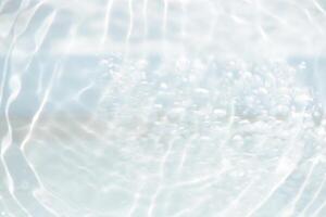 Bluewater waves on the surface ripples blurred. Defocus blurred transparent blue colored clear calm water surface texture with splash and bubbles. Water waves with shining pattern texture background. photo
