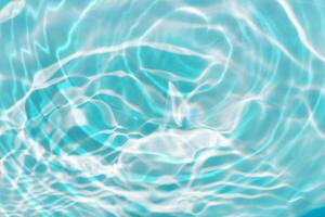 Bluewater waves on the surface ripples blurred. Defocus blurred transparent blue colored clear calm water surface texture with splash and bubbles. Water waves with shining pattern texture background. photo