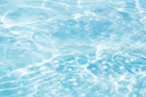 Bluewater waves on the surface ripples blurred. Defocus blurred transparent blue colored clear calm water surface texture with splash and bubbles. Water waves with shining pattern texture background. photo