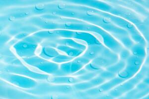 Bluewater waves on the surface ripples blurred. Defocus blurred transparent blue colored clear calm water surface texture with splash and bubbles. Water waves with shining pattern texture background. photo