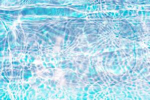 Bluewater waves on the surface ripples blurred. Defocus blurred transparent blue colored clear calm water surface texture with splash and bubbles. Water waves with shining pattern texture background. photo