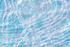 Bluewater waves on the surface ripples blurred. Defocus blurred transparent blue colored clear calm water surface texture with splash and bubbles. Water waves with shining pattern texture background. photo