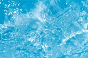 Blue water with ripples on the surface. Defocus blurred transparent blue colored clear calm water surface texture with splashes and bubbles. Water waves with shining pattern texture background. photo