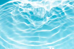 Bluewater waves on the surface ripples blurred. Defocus blurred transparent blue colored clear calm water surface texture with splash and bubbles. Water waves with shining pattern texture background. photo