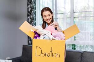 Donation Concept. Happy volunteer asian woman holding a Donate Box with full of toy doll, She working at charity center. photo