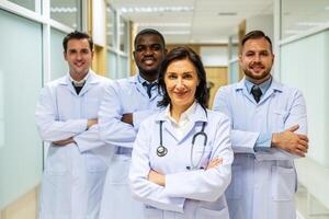 Portrait of successful team of medical doctors are looking at camera and smiling while standing in hospital photo