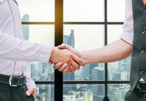 Close up of a business hand shake between two colleagues - greeting, dealing, merger and acquisition concepts on Modern glass building background photo