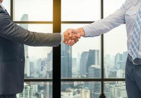 Close up of a business hand shake between two colleagues - greeting, dealing, merger and acquisition concepts on Modern glass building background photo