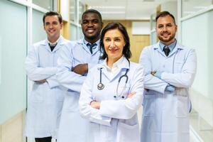 retrato de exitoso equipo de médico doctores son mirando a cámara y sonriente mientras en pie en hospital foto