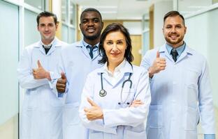 Portrait of successful team of medical doctors are looking at camera and smiling while standing in hospital photo