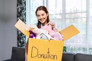 Donation Concept. Happy volunteer asian woman holding a Donate Box with full of toy doll, She working at charity center. photo
