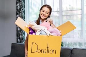 Donation Concept. Happy volunteer asian woman holding a Donate Box with full of toy doll, She working at charity center. photo