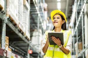 Portrait of smiling asian woman business using digital tablet checking amount of stock product inventory on shelf at distribution warehouse factory, Logistics business planning concept photo