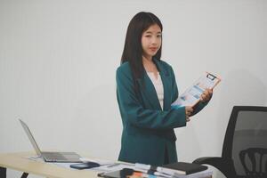 Asian Business woman using calculator and laptop for doing math finance on an office desk, tax, report, accounting, statistics, and analytical research concept photo