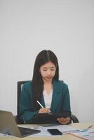 Beautiful Asian businesswoman work using a tablet and a laptop with documents placed at the office. photo