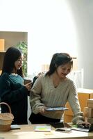 Startup small business SME, Entrepreneur owner African woman using smartphone or tablet taking receive and checking online purchase shopping order to preparing pack product box. photo