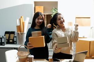 Startup small business SME, Entrepreneur owner African woman using smartphone or tablet taking receive and checking online purchase shopping order to preparing pack product box. photo