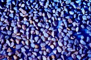 Multi colored pebbles light stones,positive tone, blue abstract background photo