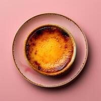 Close-up of a delicious creme brulee dessert with a crispy caramelized sugar topping on a pink plate. photo