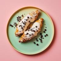 Two delicious croissants with white frosting and chocolate sprinkles on a teal plate, top view. Freshly baked pastry on a pink background. photo