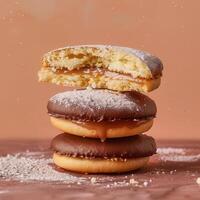 Close-up of stacked chocolate and caramel filled cookies with powdered sugar on top, concept of sweet treat, dessert, and bakery. photo
