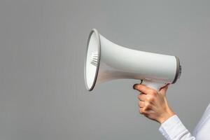 Hand holding a megaphone on a gray background photo