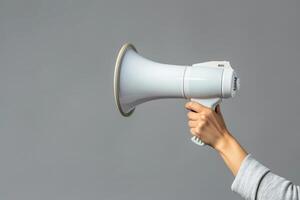 Hand holding a megaphone on a gray background photo