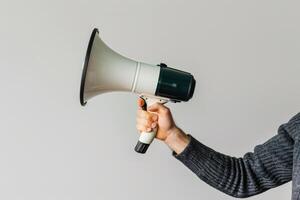 Hand holding a megaphone on a neutral background photo