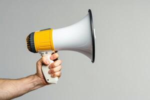 Hand holding a megaphone on a gray background photo