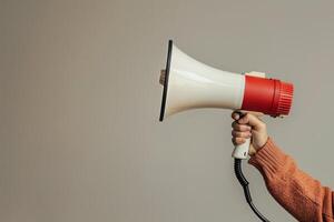 Hand holding a megaphone on a beige background photo
