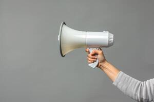 Hand holding a megaphone on a neutral background photo