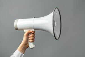 Hand holding a megaphone on a gray background photo