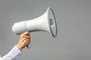 Hand holding a megaphone on a plain background photo