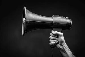 Hand holding a megaphone on a dark background photo