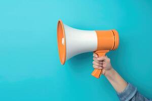 Hand holding a megaphone on blue background photo