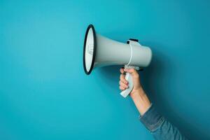 Hand holding a megaphone against blue background photo