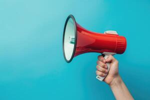 Hand holding a red megaphone against a blue background photo