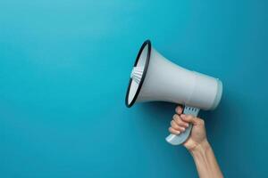 Hand holding a megaphone on blue background photo